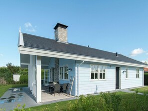 A light blue house with a covered patio, a chimney, and a garden. - Well-furnished Home With a Porch Near the Sea (Noordwijk)