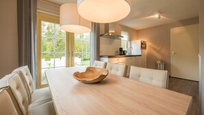 Ein moderner Essbereich mit Holztisch, weißen Polsterstühlen und Pendelleuchten.