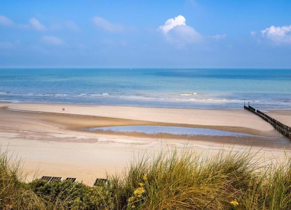 A beach with a wooden walkway and a clear sky.