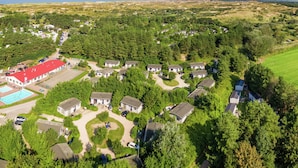 Vista aérea de una zona residencial con casas, una piscina y un campo grande.