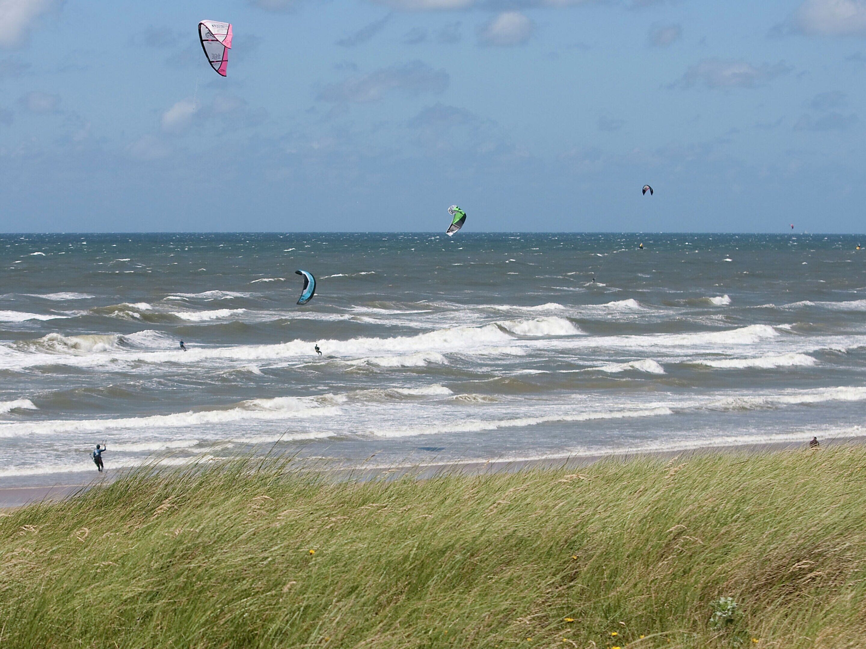 A beach with waves and kites.