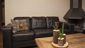 Un salon moderne avec un canapé en cuir noir, une table basse en bois et une cheminée.