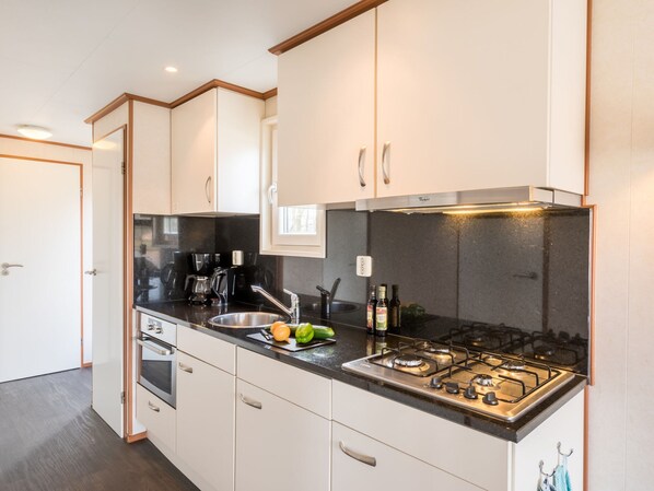 Une cuisine moderne avec des meubles blancs, un plan de travail noir, une cuisinière et un évier.