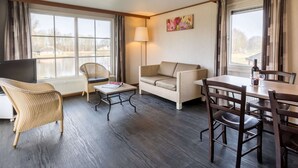 Ett hotellrum med ett stort fönster, en soffa, ett matbord och en stol.