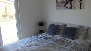 Ein Schlafzimmer mit einem Bett, einem Nachttisch mit Lampe und einem Wandbild.