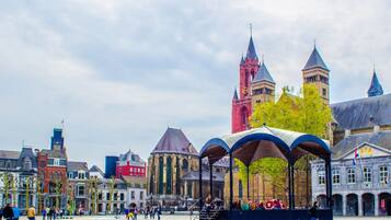 A historic square with a prominent church tower, a covered seating area, and traditional buildings.