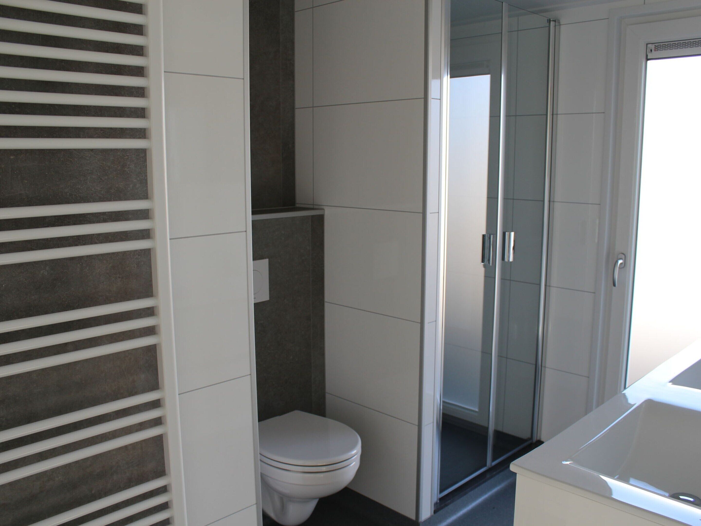 A modern bathroom with a toilet, a glass shower enclosure, and a bathtub.