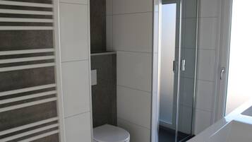 A modern bathroom with a toilet, a glass shower enclosure, and a bathtub.