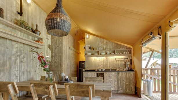 A rustic wooden interior with a dining area, kitchen, and a view of the outdoors. - Apartment in Netherlands Near Scenic Canals (Uden)