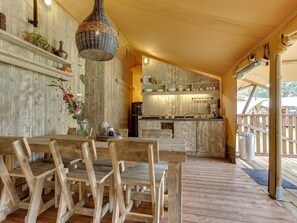 A rustic wooden interior with a dining area, kitchen, and a view of the outdoors. - Apartment in Netherlands Near Scenic Canals (Uden)