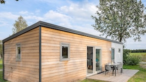 A small wooden cabin with a patio and a table with chairs. - Chalet Near Hunebedcentrum (Borger)