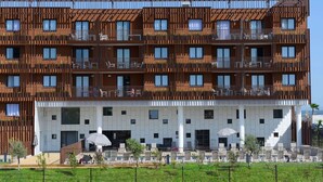 Ett hotell med flera våningar, balkonger, utomhusservering och en vit fasad.