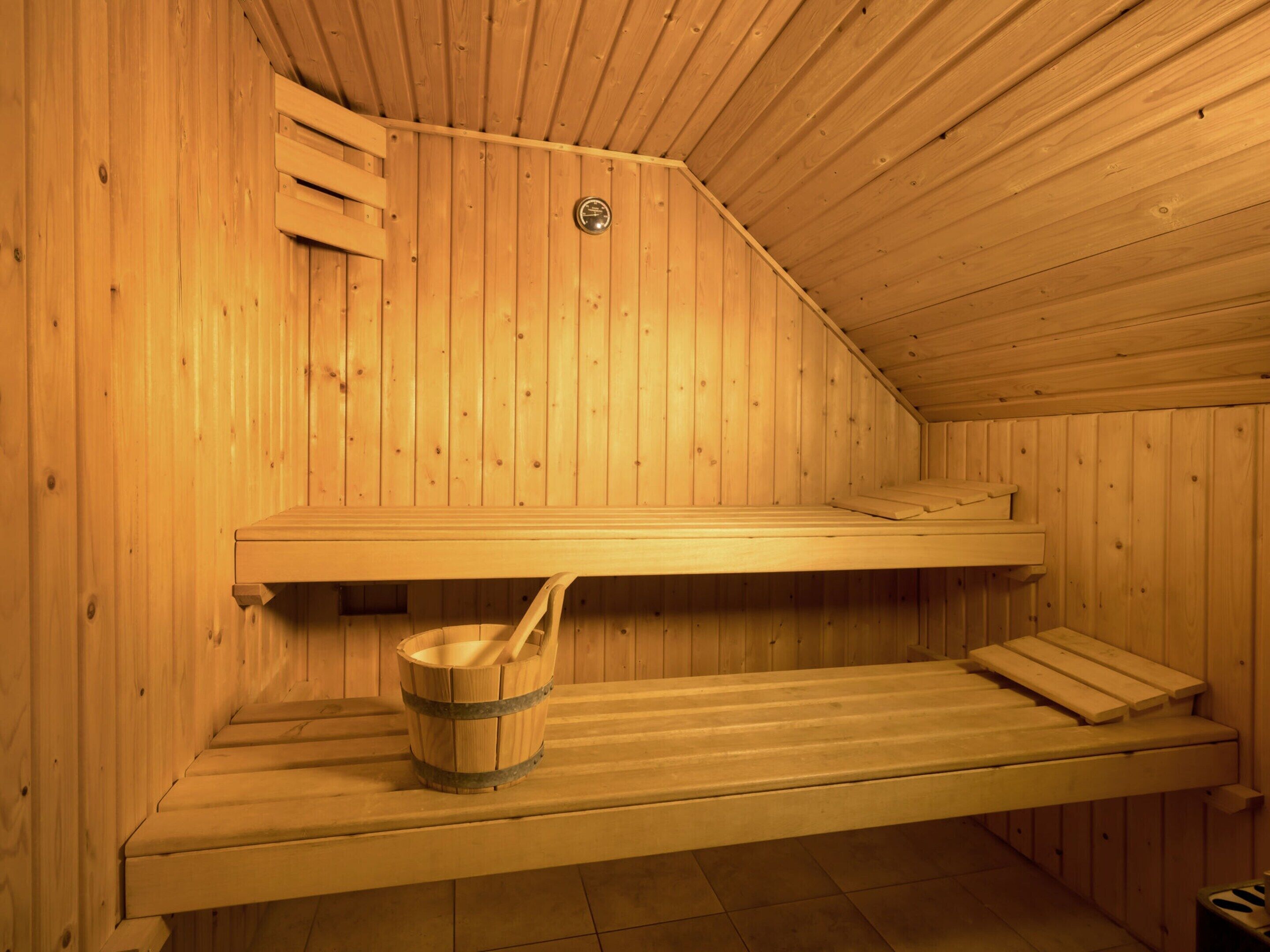 A sauna with wooden benches and a wooden bucket.
