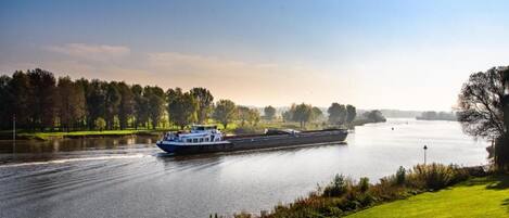 A river with a boat, grassy banks, and trees in the background.