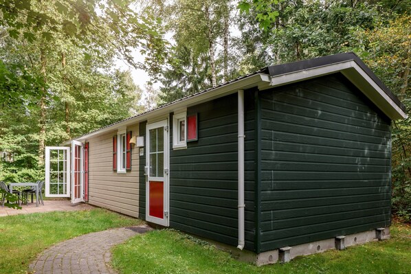 A small, single-story cabin with a green exterior, a red door, and a white-framed window. - Cozy Chalet in Borger Woods (Borger)