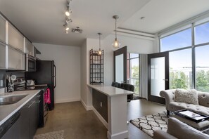 Una cucina moderna con elettrodomestici in acciaio inossidabile, un'area pranzo con isola bianca e un'ampia finestra con vista sulla città.