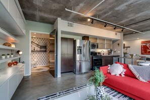 A modern kitchen with stainless steel appliances, a red sofa, and a minimalist design.