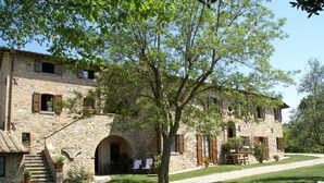 A stone building with a staircase leading to an entrance, surrounded by a well-maintained lawn and trees. - Holiday Home in Montone With Swimming Pool (Montone)