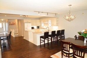 A spacious kitchen with a central island, dark wooden flooring, and white cabinetry.