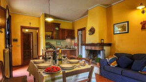 A dining area with a table set for four, a sofa, and a kitchen in the background. - Tuscan Retreat With Pool (Cortona)