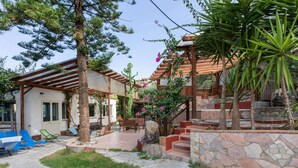 A covered patio area with outdoor seating, a stone staircase, and a wooden pergola.
