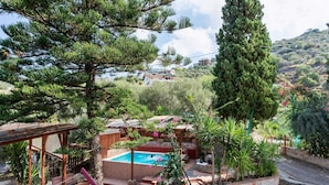 A pool area with a wooden deck, a hammock, and a stone wall surrounding the pool.
