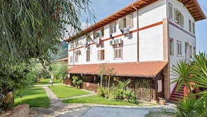 A two-story building with a red-tiled roof, a covered patio, and a garden with a stone pathway.