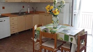 Una cocina con armarios de madera, una mesa de comedor con mantel verde y blanco, y un florero con flores.