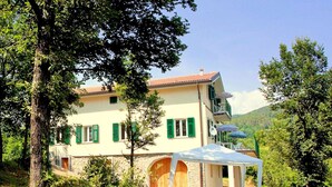 A two-story house with a stone facade, green shutters, and a balcony. - Holiday Home in Sesta Godano Near Lake (Sesta Godano)