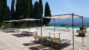 A poolside area with sun loungers, umbrellas, and a view of the mountains. - Scenic Apartment With Pool (Figline e Incisa Valdarno)