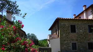 A stone building with a tiled roof, a small balcony, and a gravel courtyard. - Scenic Apartment With Pool (Figline e Incisa Valdarno)