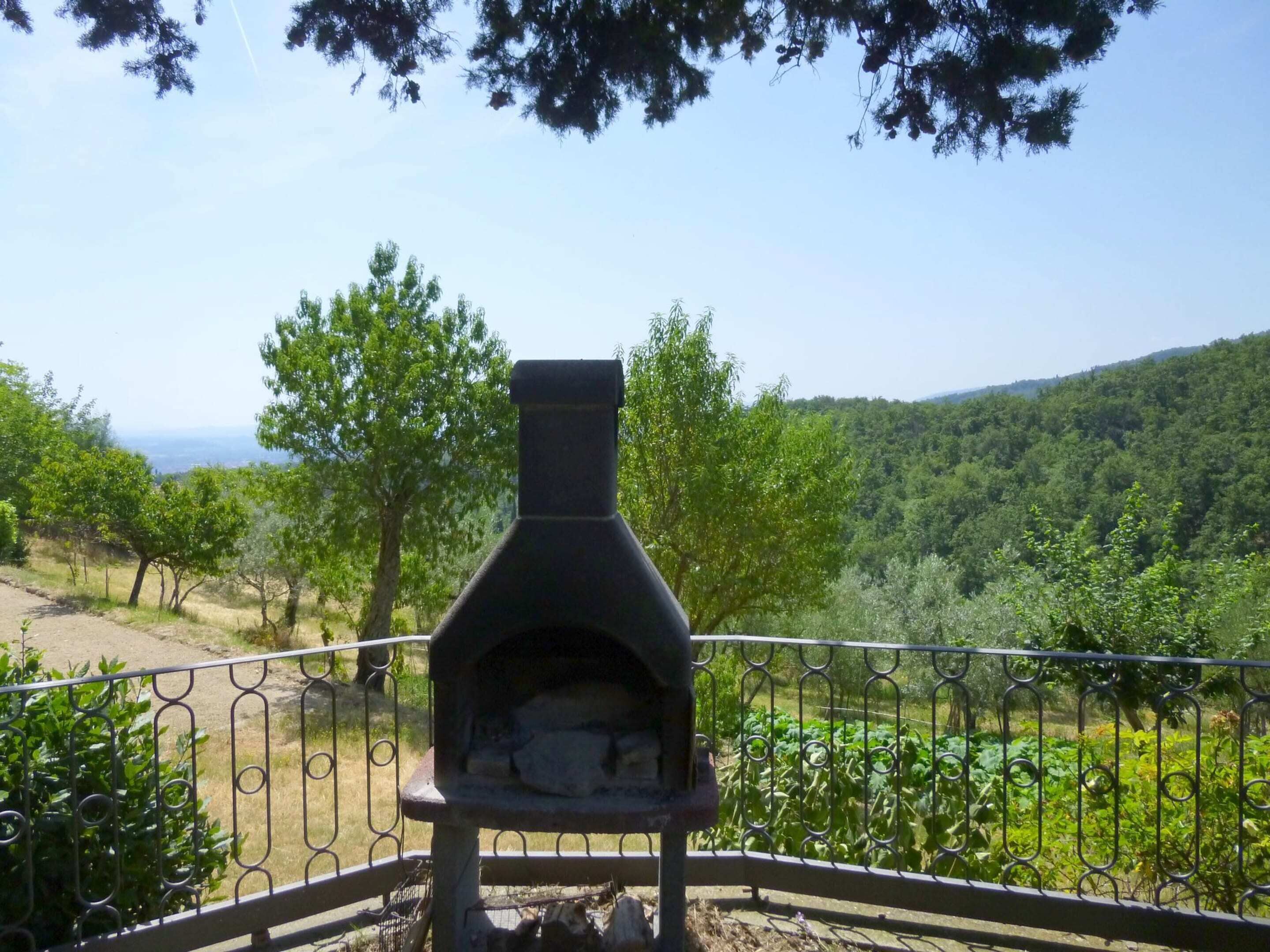 An outdoor stone oven with a metal railing in a natural setting.