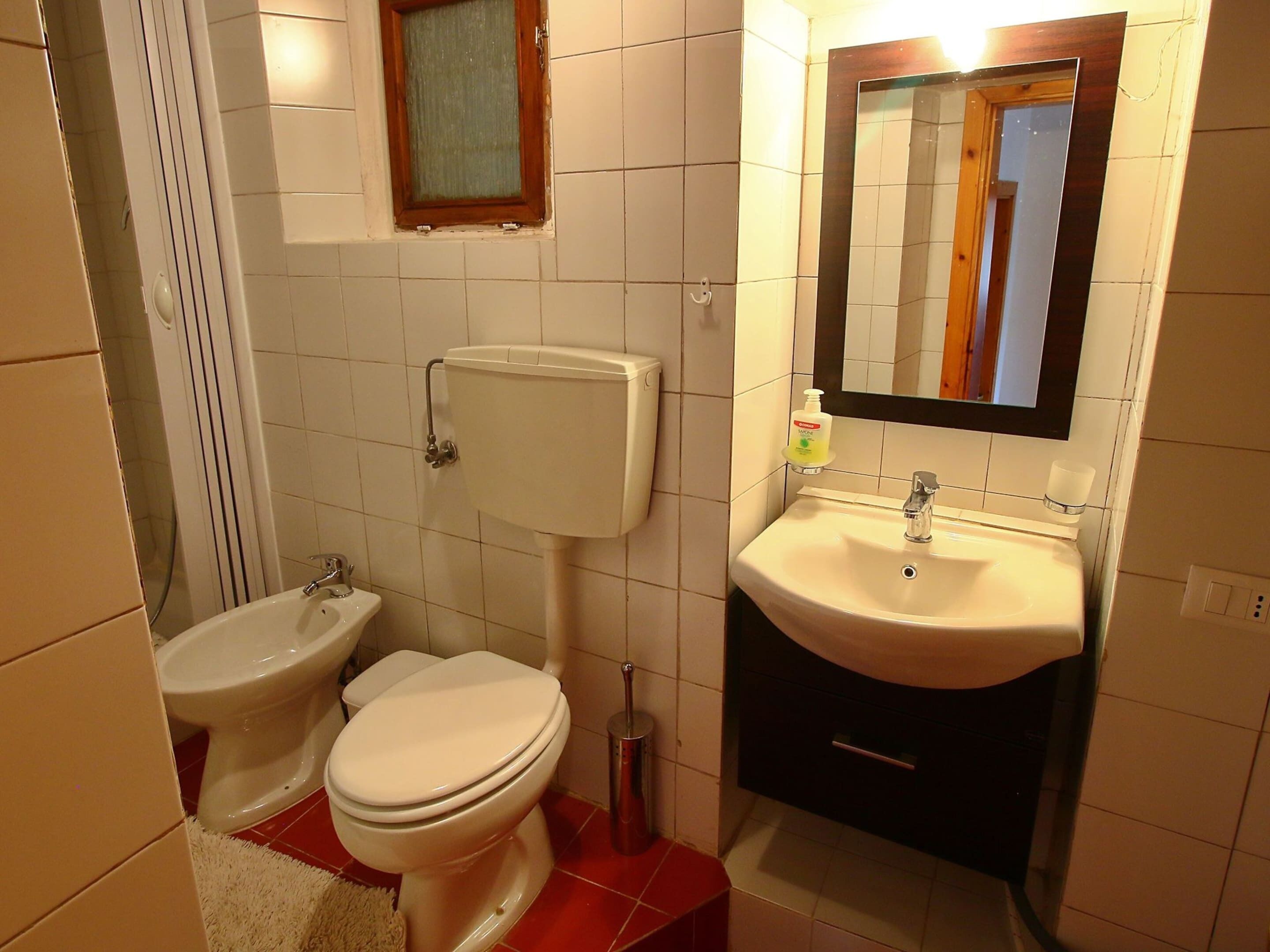 Een kleine badkamer met toilet, wastafel en bidet.
