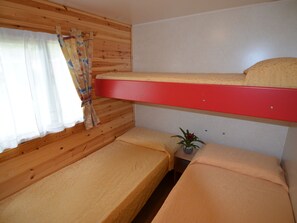 Une chambre avec un lit superposé, une petite table et une plante en pot.