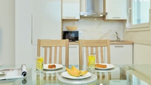 A dining table with two chairs, a glass of juice, a plate with melon slices, and a plate with a croissant.