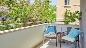 A balcony with wicker chairs, a small table, and a potted plant.