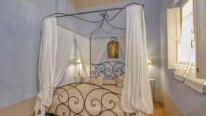 A four-poster bed with white drapes, a decorative headboard, and two bedside lamps. - Tuscan Stay w/ Jacuzzi (Grosseto)