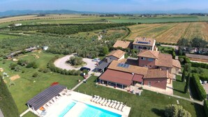 An aerial view of a residential area with a large swimming pool, multiple houses, and surrounding fields. - Tuscan Stay w/ Jacuzzi (Grosseto)