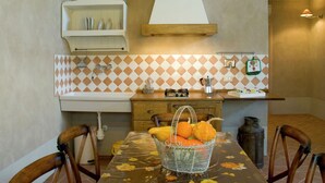A compact kitchen with a sink, stove, and a dining table with chairs. - Tuscan Stay w/ Jacuzzi (Grosseto)