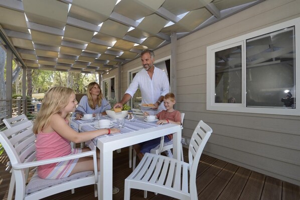 Un espace extérieur abrité, aménagé pour prendre les repas, avec une table dressée pour un repas de famille.