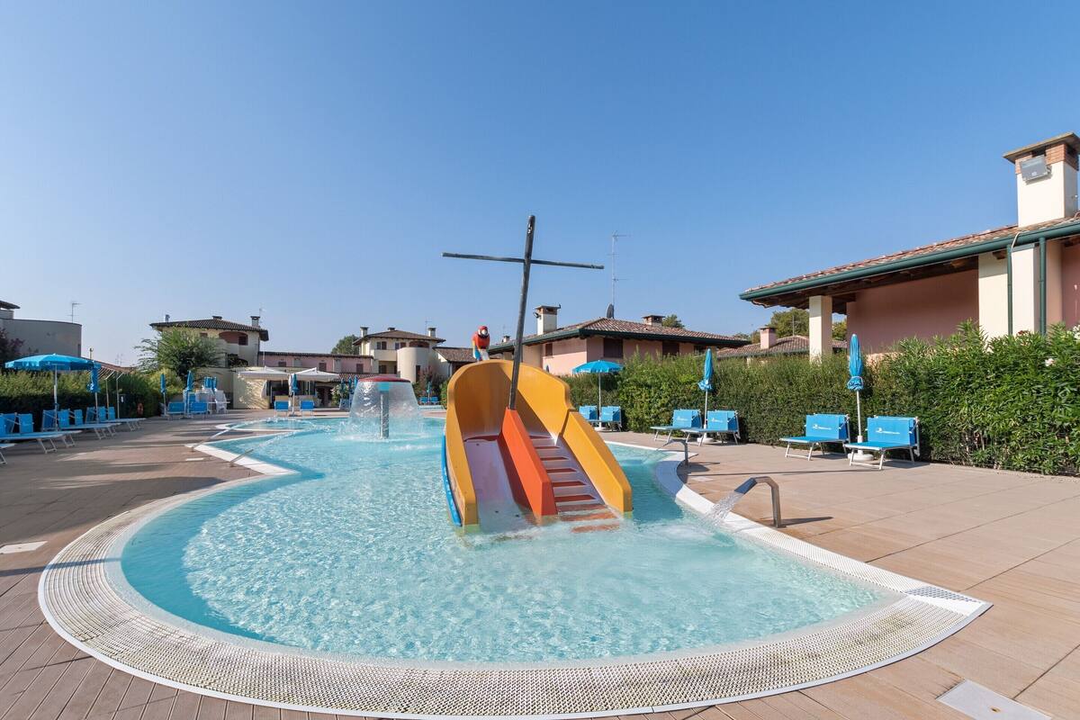 A swimming pool with a slide, lounge chairs, and umbrellas.
