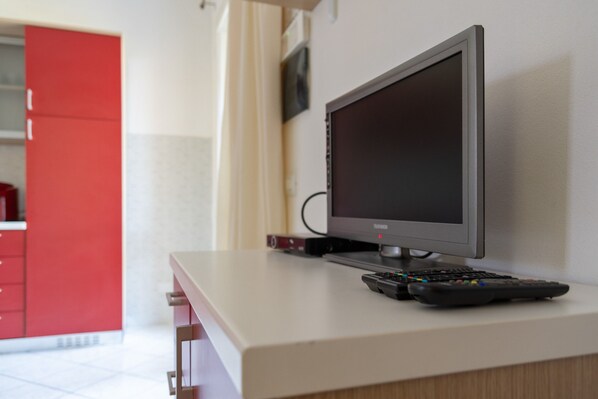 A television on a white surface with a remote control beside it. - Sunny Coastal Escape in Lido (Comacchio)