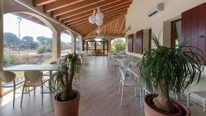 Un espace patio intérieur agrémenté de poutres en bois, de chaises blanches et de plantes en pot.