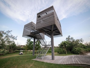 Eine moderne Außenanlage mit Holzterrasse und Metalltreppe, umgeben von Grünflächen.