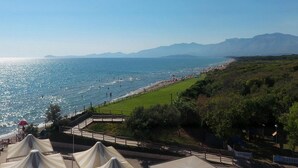 A coastal view with a beach, grassy areas, and a mountain range in the background. - Chalet in Baia Domizia With Private Beach (Cellole)