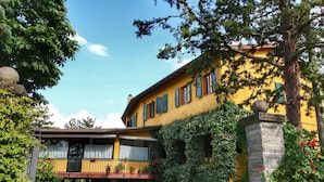 A yellow building with a balcony and a stone pillar with red flowers. - _x000d_
boutique Villa With Pool (Anghiari)