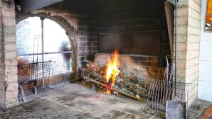 A fireplace with a fire burning inside, surrounded by stone walls and a window. - _x000d_
boutique Villa With Pool (Anghiari)