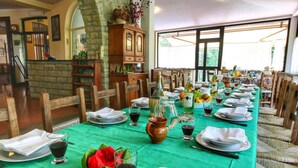 A long dining table set with plates, glasses, and cutlery, surrounded by wooden chairs in a room with stone walls and large windows. - _x000d_
boutique Villa With Pool (Anghiari)