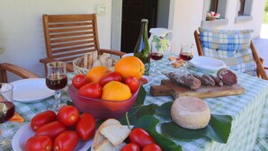 A table set for a meal with a variety of foods and drinks, including bread, tomatoes, cheese, and wine, in an outdoor setting with chairs and a tablecloth. - Belvilla by OYO Eolo (Apecchio)