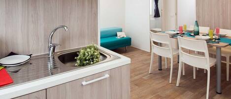 A modern kitchen with a sink, cabinets, and a dining area with a table and chairs.